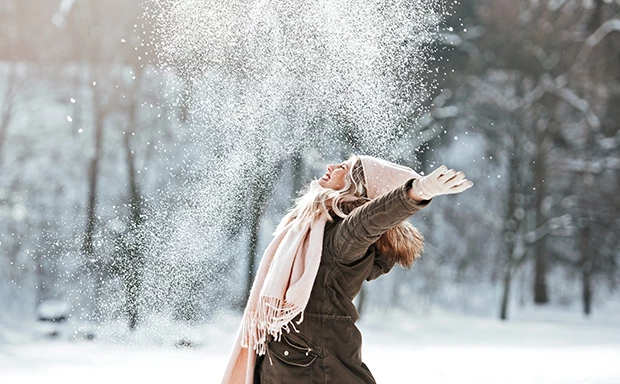 woman wearing a pink scarf and hat outside in the snow