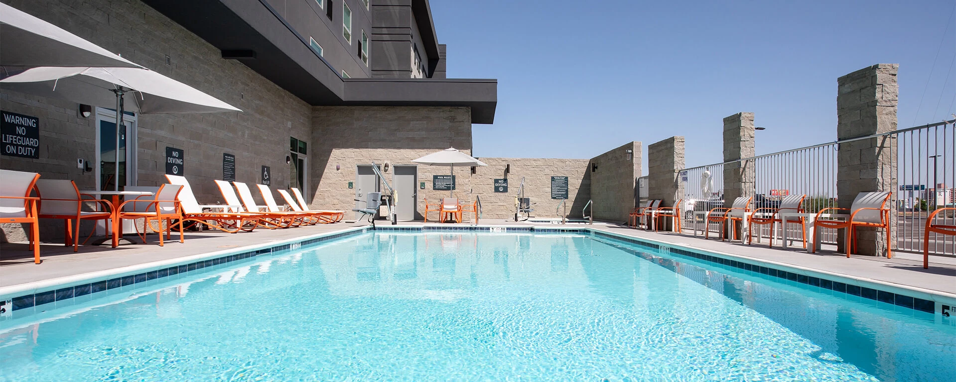view of the pool with orange and white pool chairs along the side of it