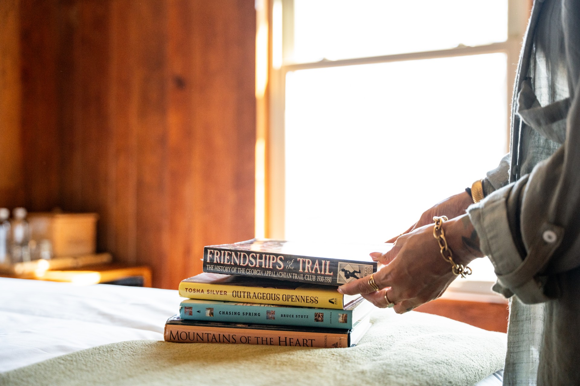 a person's hand reaching over a stack of books