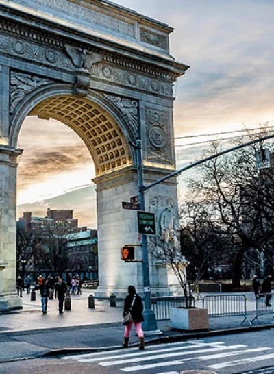a large stone arch in a city with people walking around