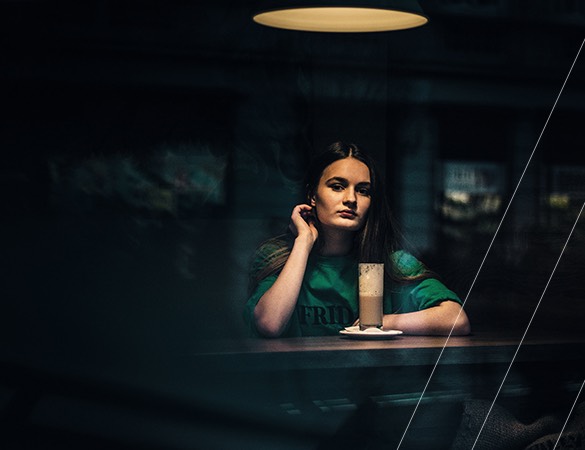 a woman sitting at a dark bar with a light over her