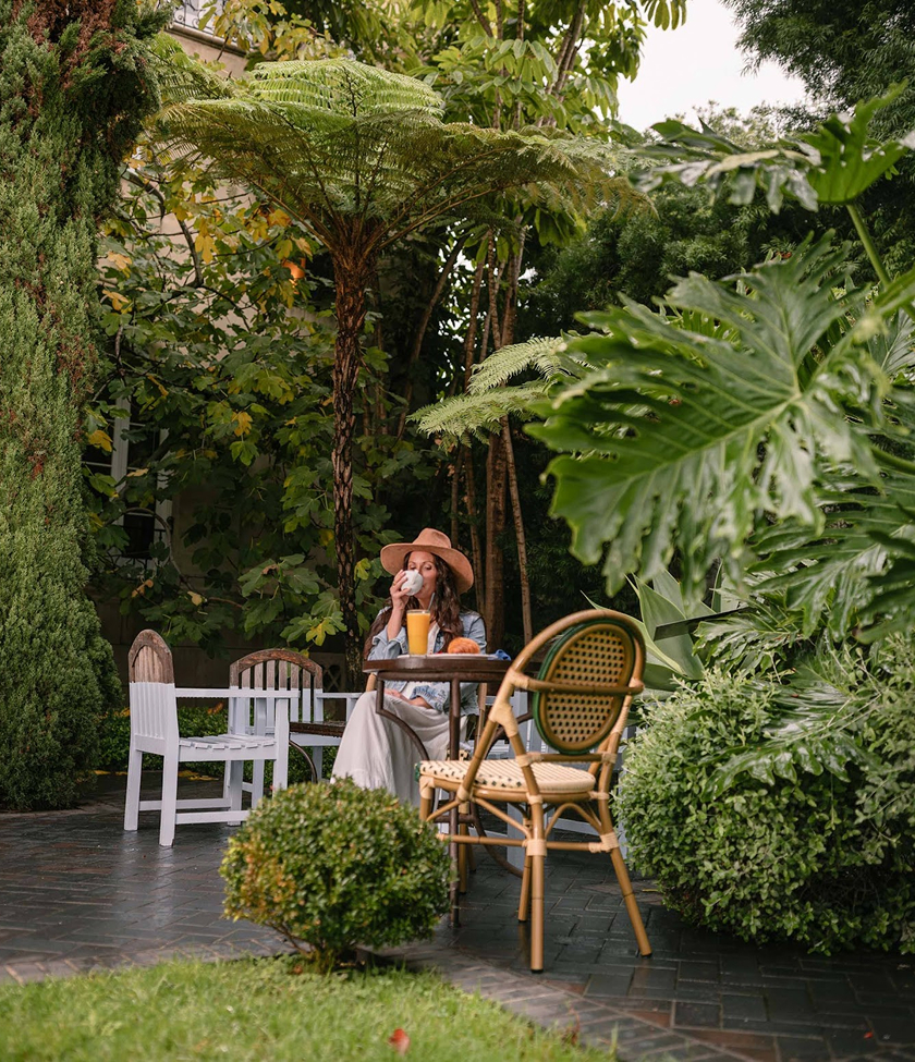 a woman sitting at a table in a garden