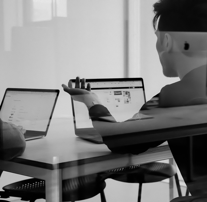 a man sitting at a table with laptops