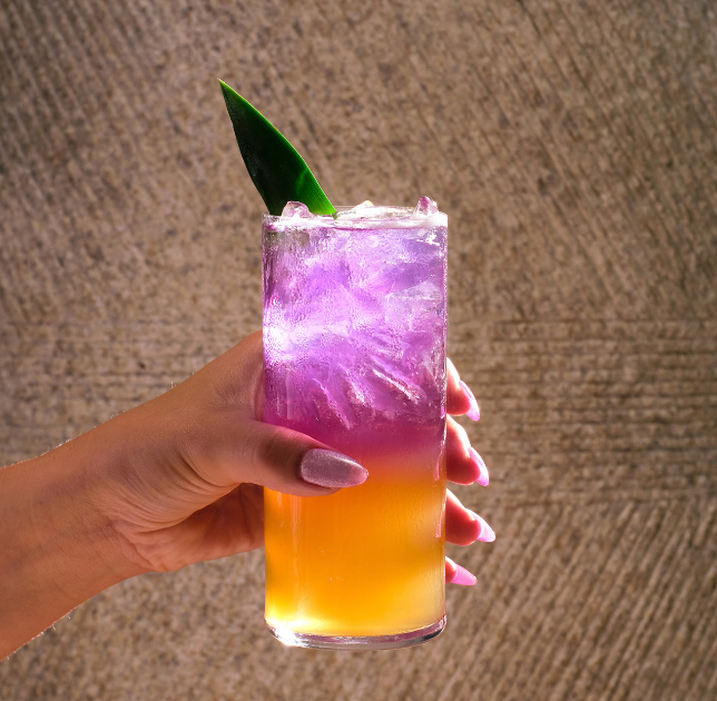 a hand holding a glass of liquid