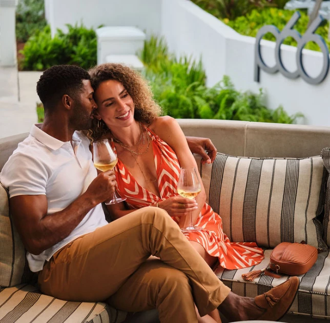 a man and woman sitting on a couch with wine glasses
