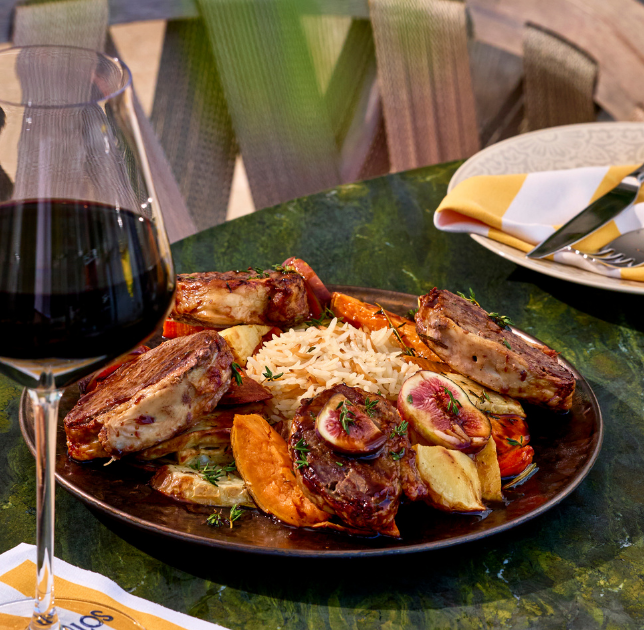 a plate of meat and rice with a glass of wine