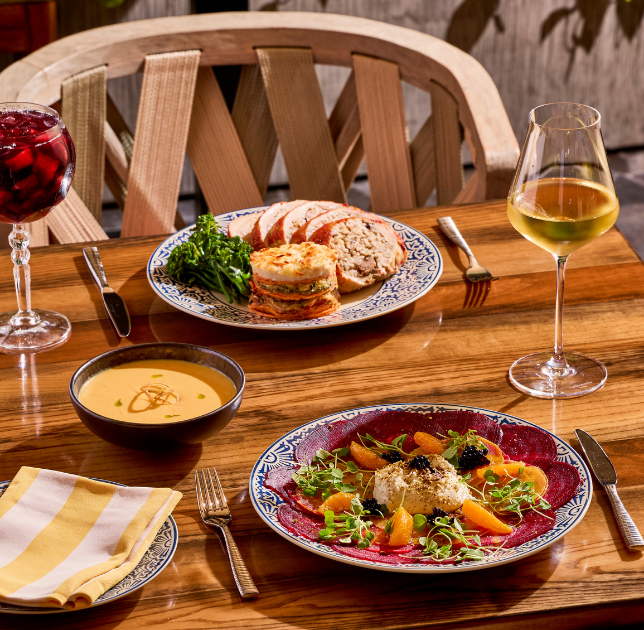 a table with plates of food and glasses of wine