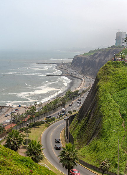 a road with cars on the side of a cliff by the ocean