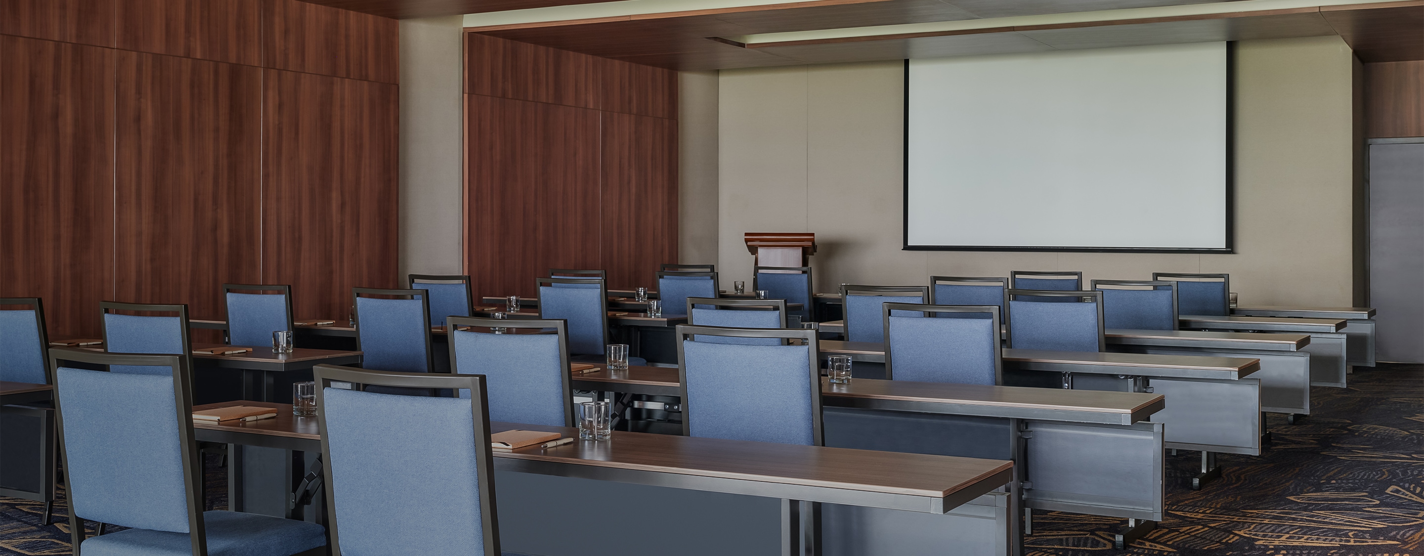 a room with blue chairs and a projector screen