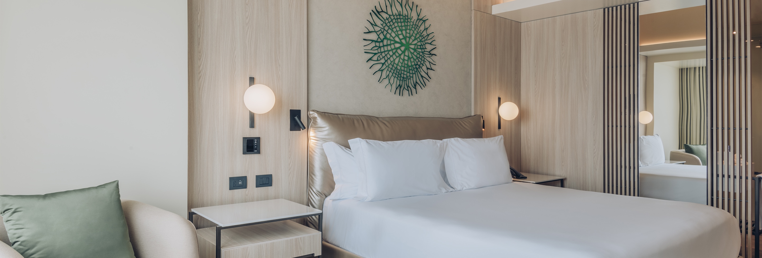 a bed with white sheets and a lamp on the wall