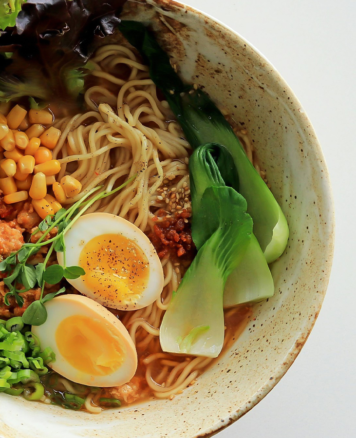 a bowl of ramen with vegetables and eggs