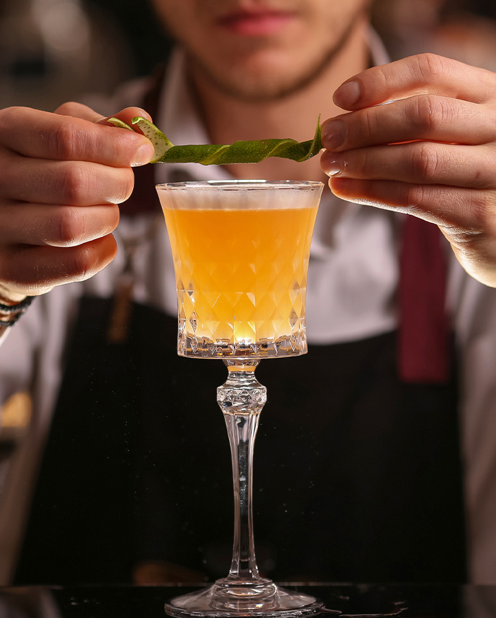 a person holding a leaf over a glass of drink