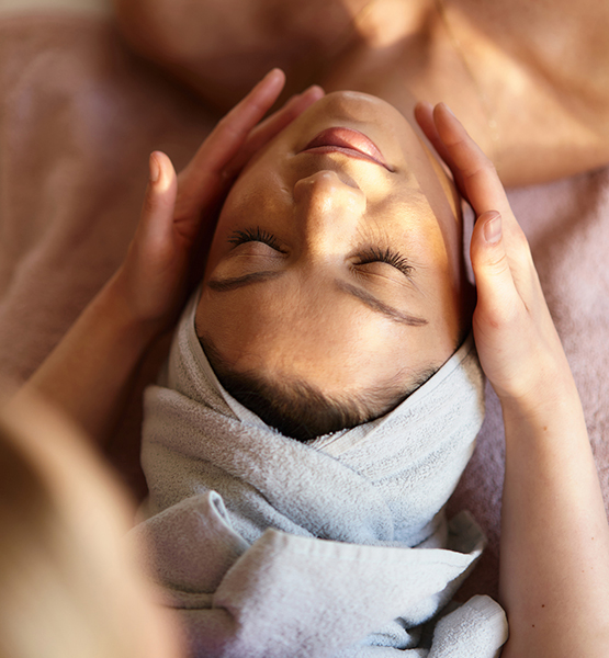 a woman lying down with her eyes closed and a towel around her head