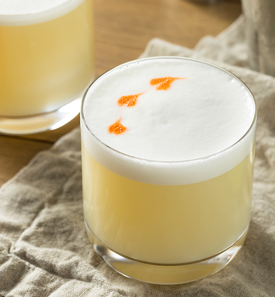 a glass of yellow liquid with orange and white foam