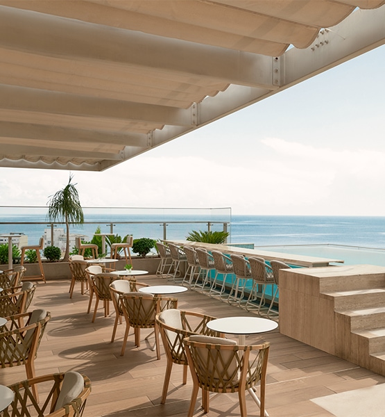 a patio with chairs and a pool overlooking the ocean