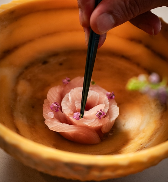 a person holding chopsticks to a piece of food