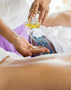 a person pouring oil onto a person's back