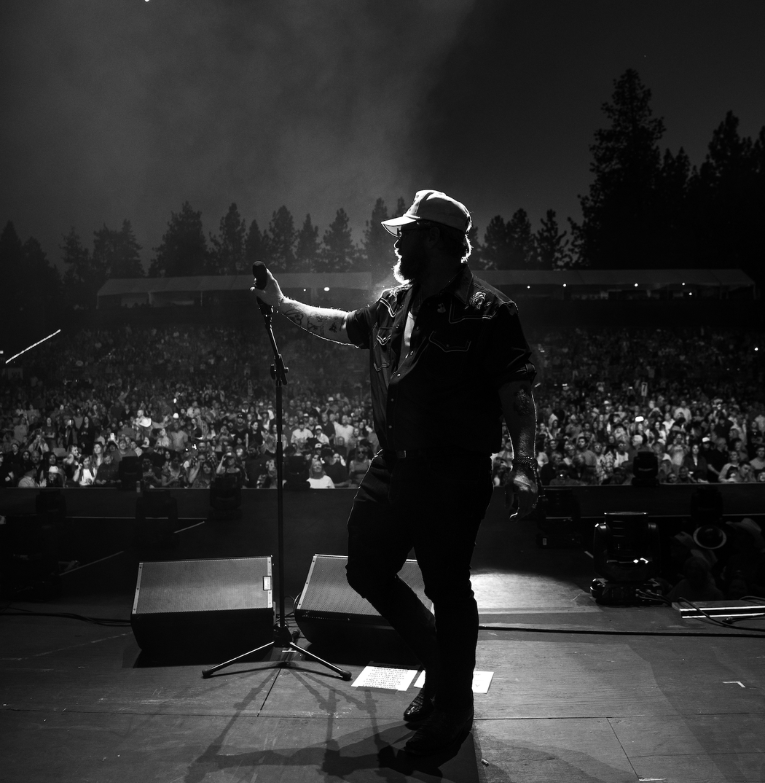 a man on stage with a microphone and a crowd of people