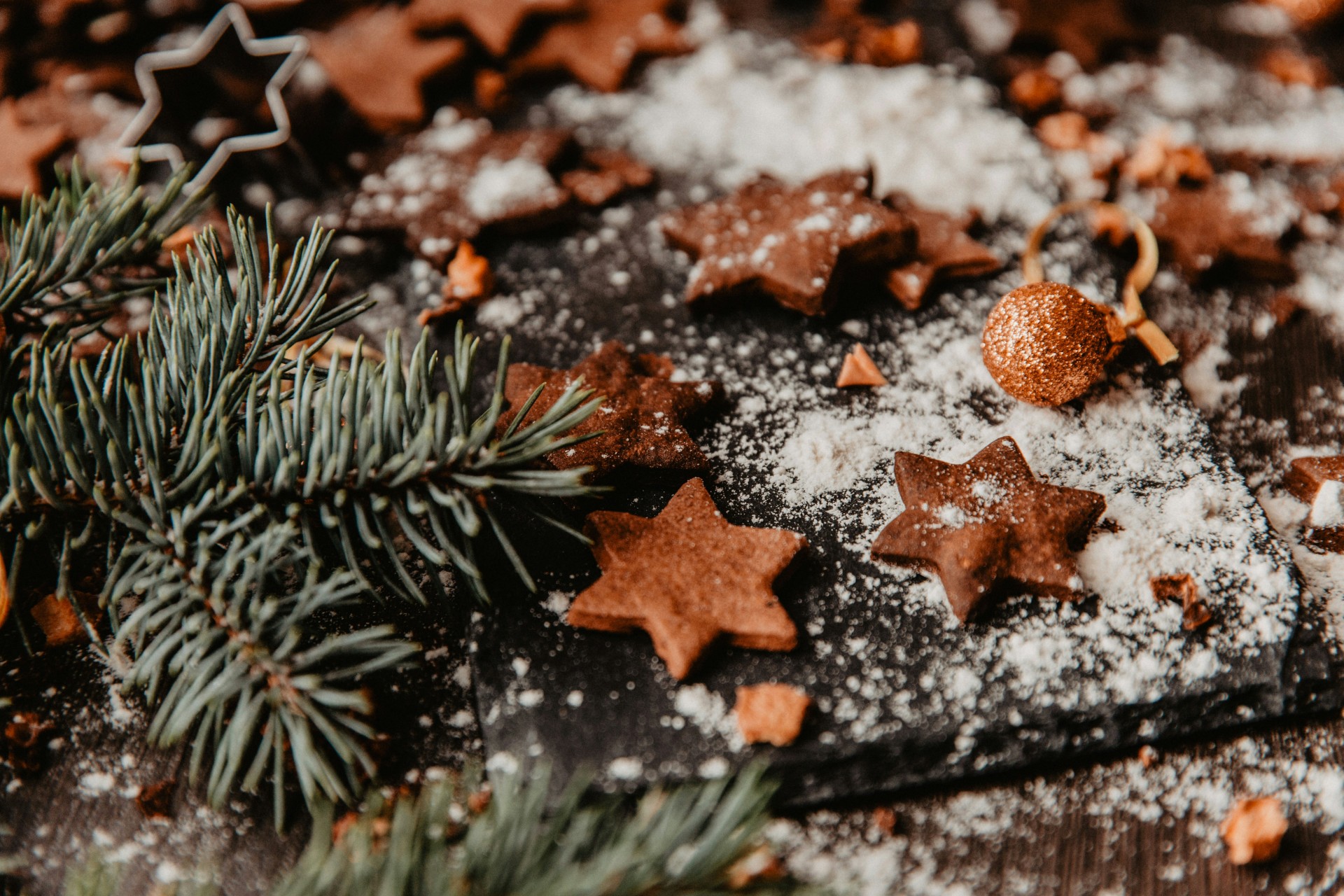 a star shaped cookies on a black surface with a branch of pine