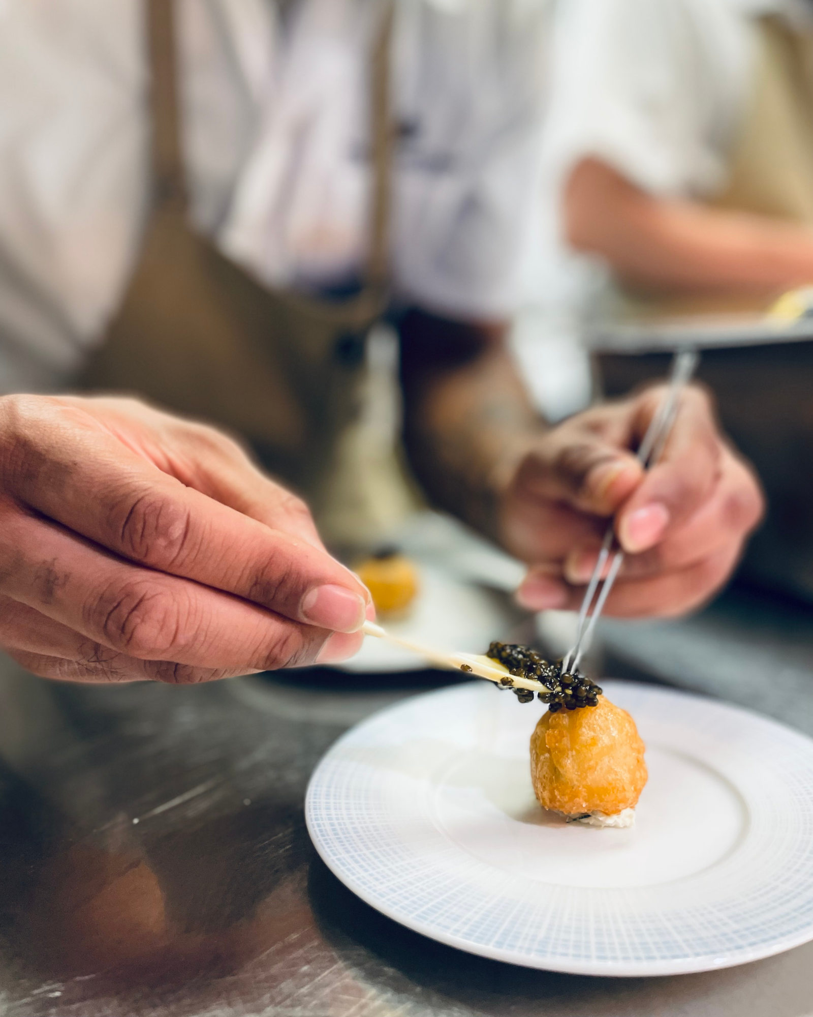 a person holding chopsticks over a small round object