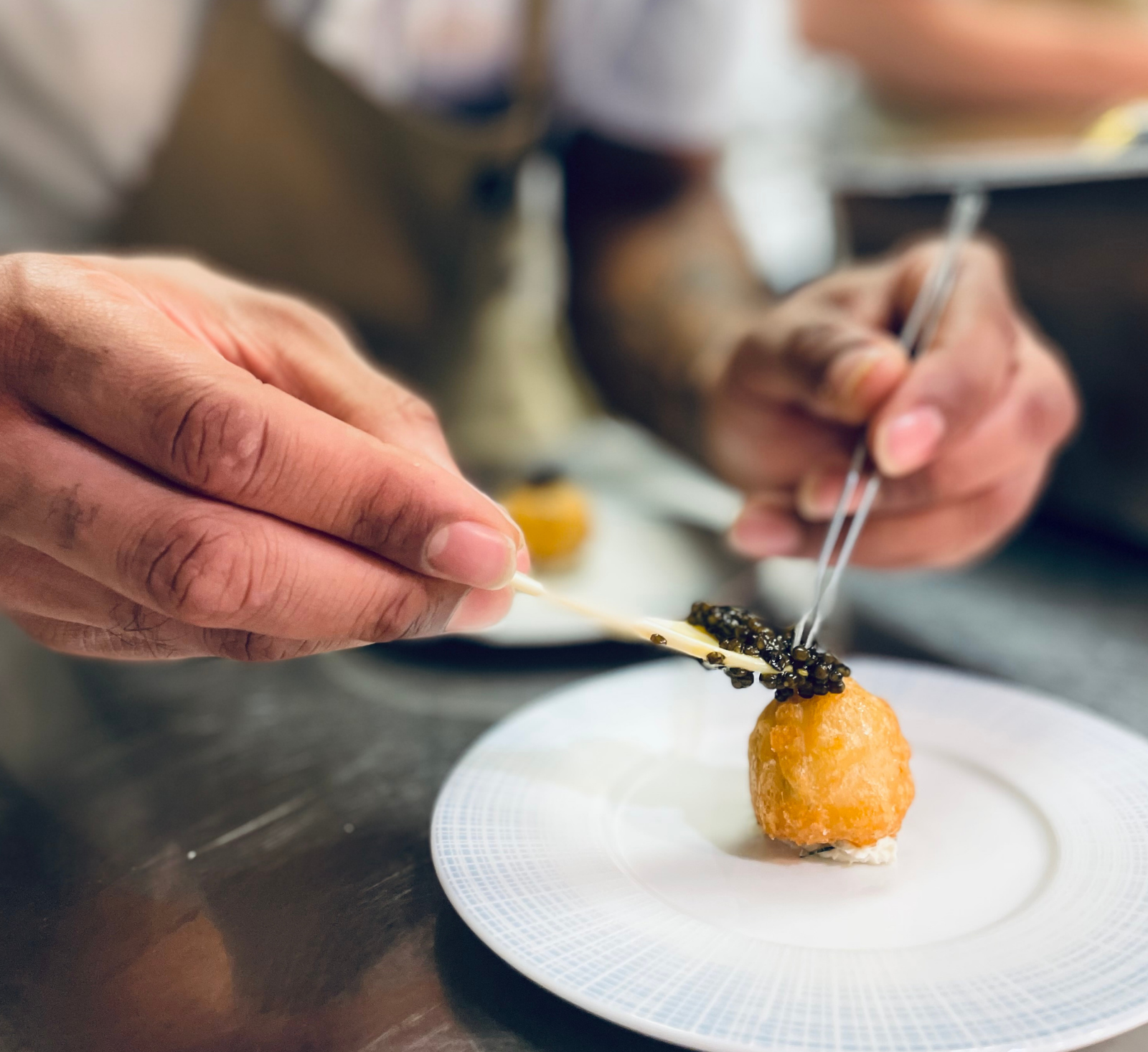 a person holding chopsticks over a small round object