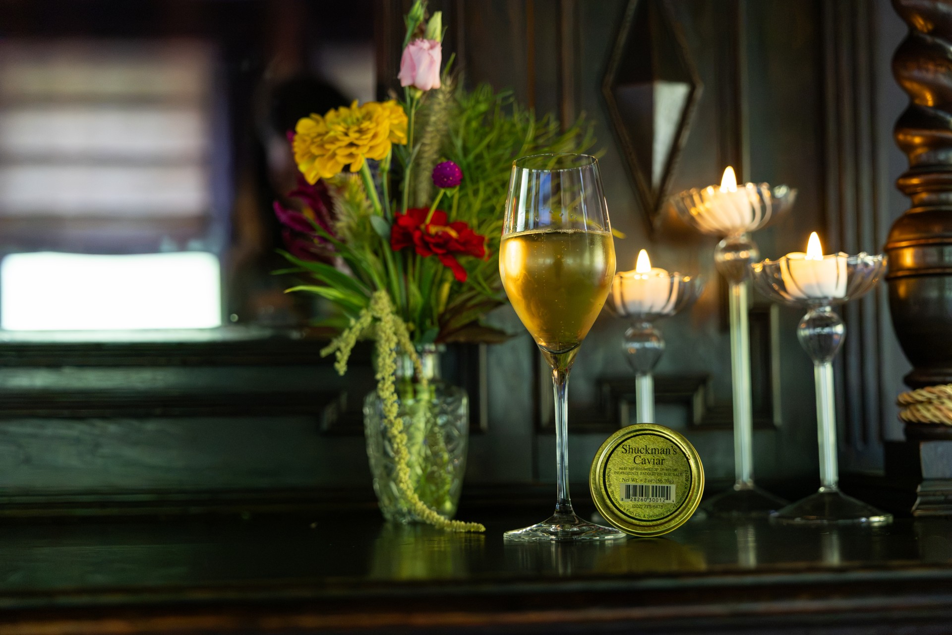 a glass of wine next to a vase of flowers
