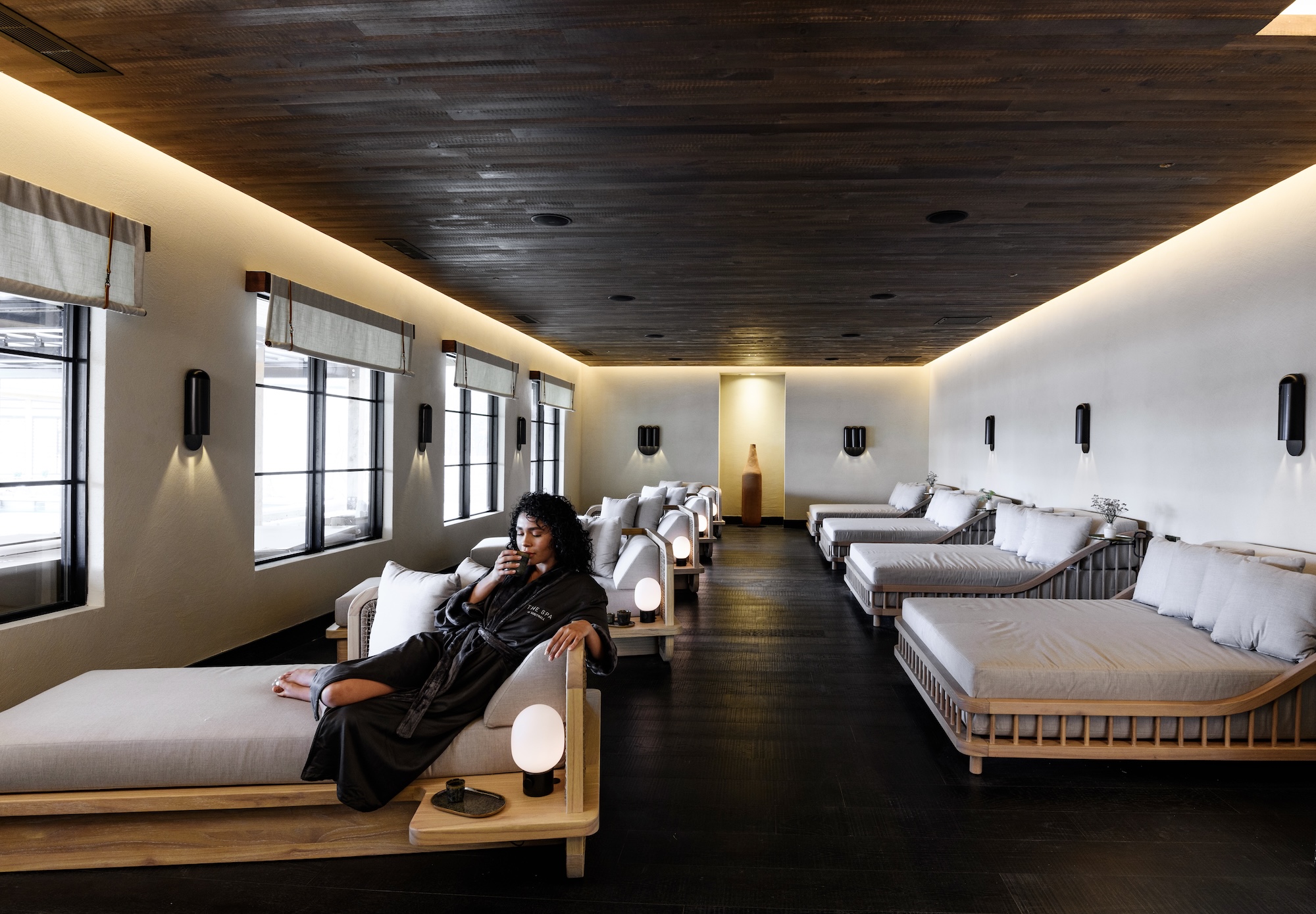 a woman sitting on a couch in a room with many beds