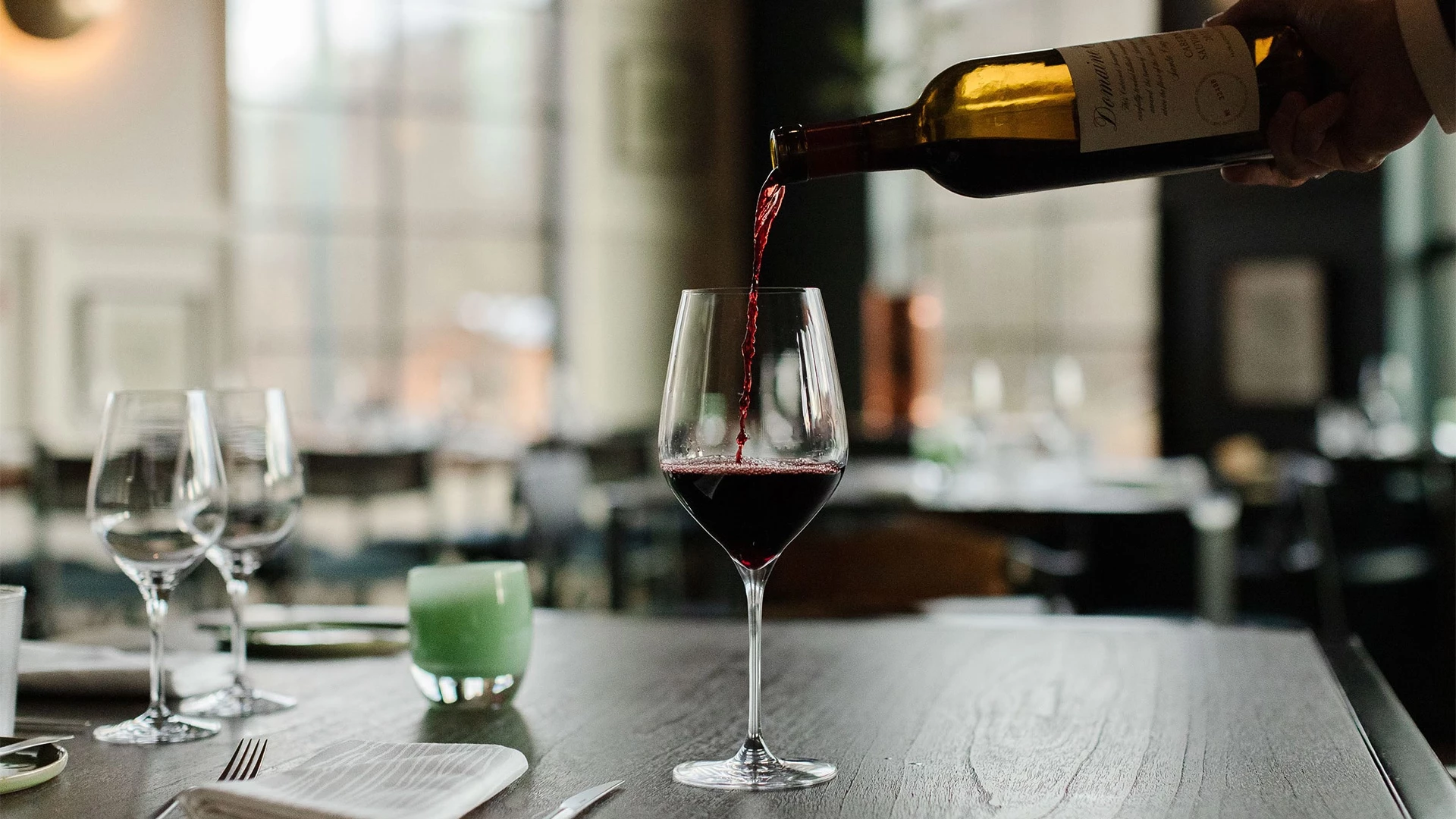 a person pouring wine into a glass