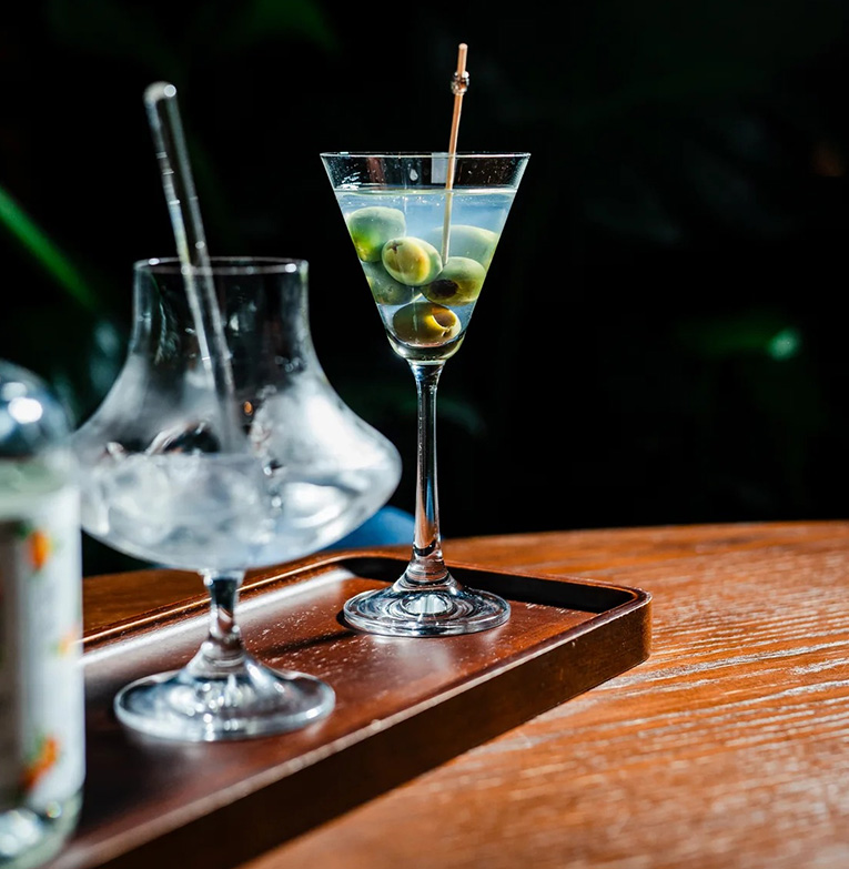 a martini glass with olives on a tray