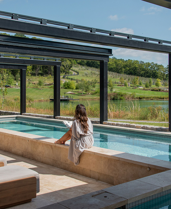 a woman sitting on a ledge of a pool