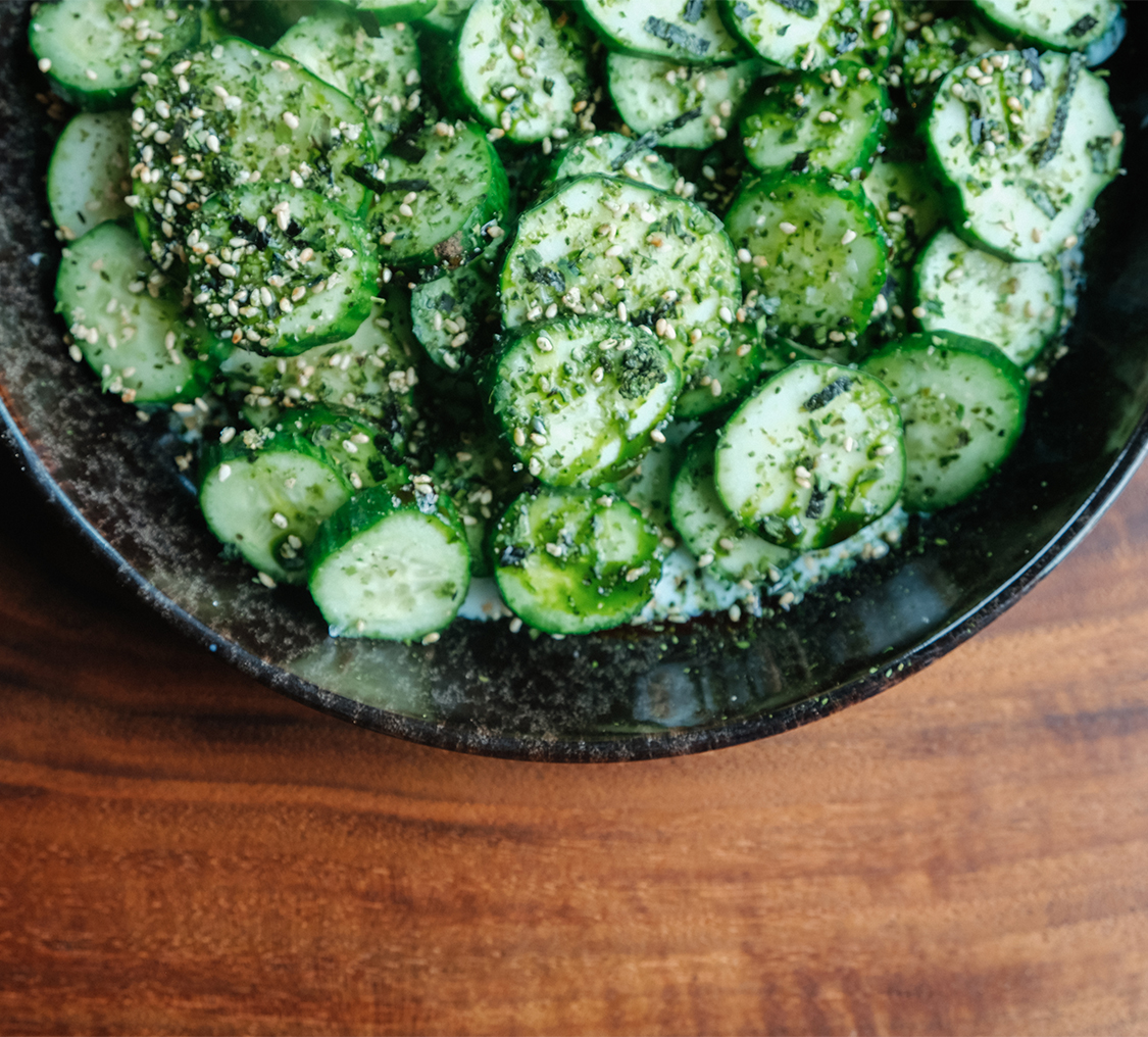 a bowl of cucumbers on a wood surface