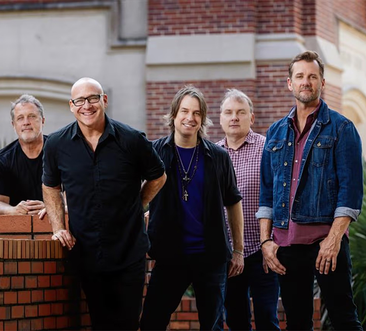 a group of men standing in front of a brick wall