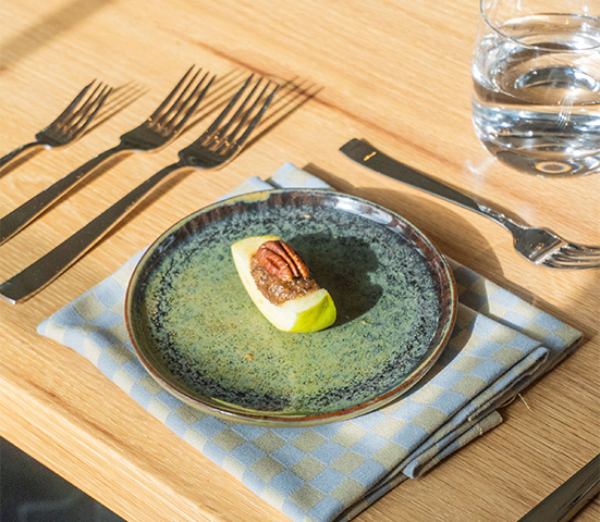 a plate with a piece of fruit on it and silverware on a table