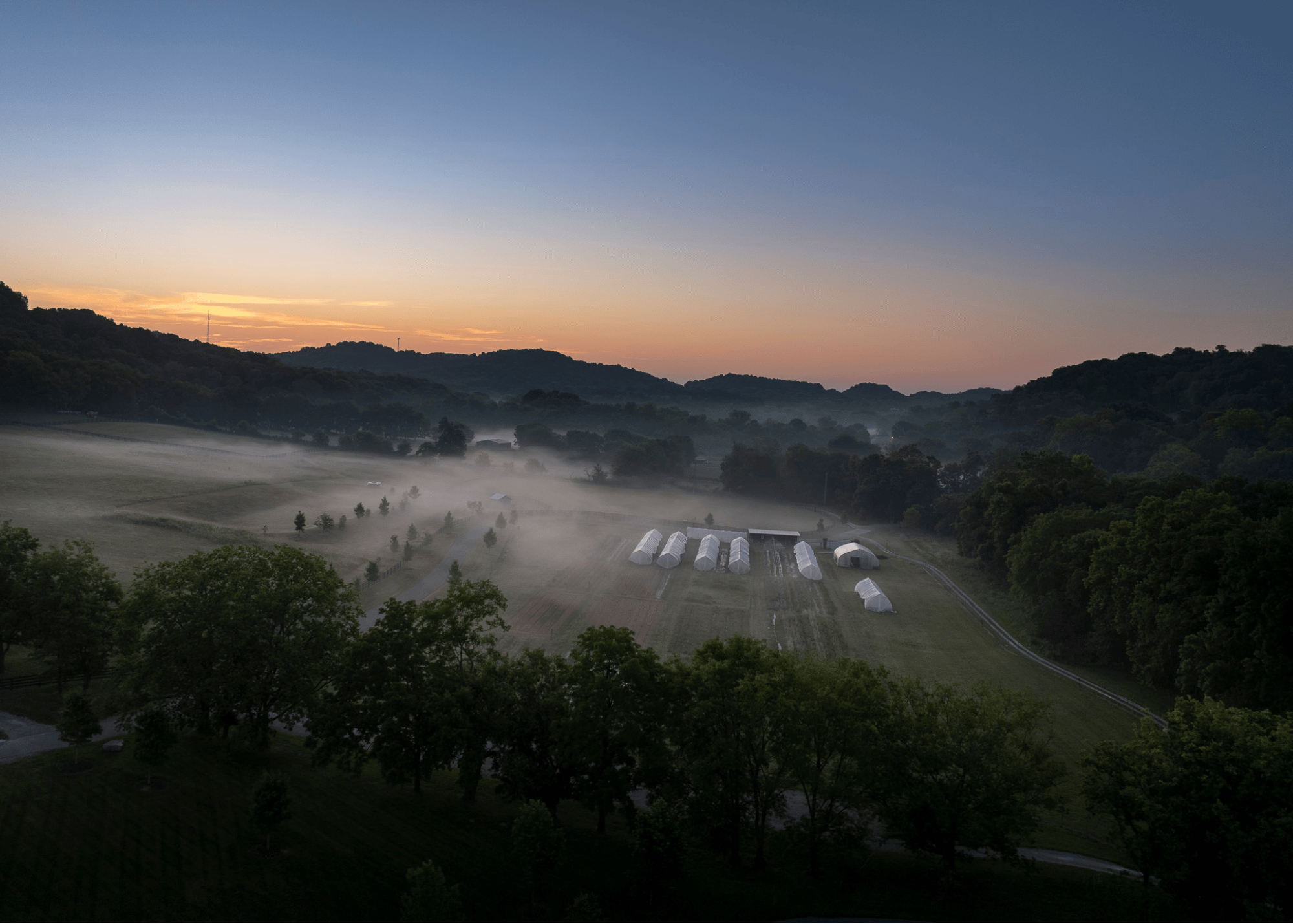 a field with tents and trees in the background