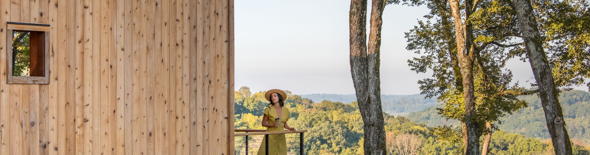 a woman standing on a balcony with trees in the background