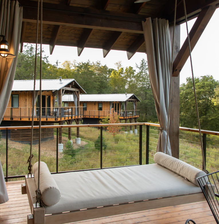 a porch swing with a view of a house and trees
