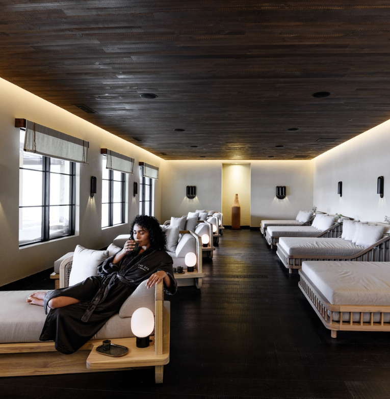a woman sitting on a couch in a room with many white beds