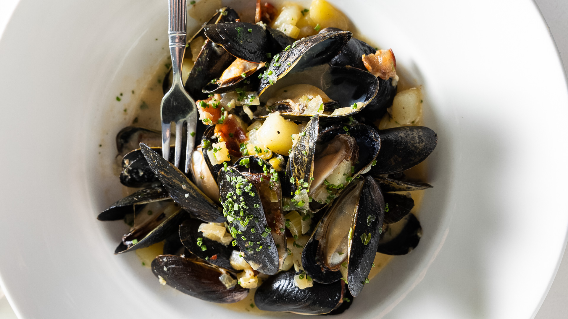 a bowl of mussels with a fork