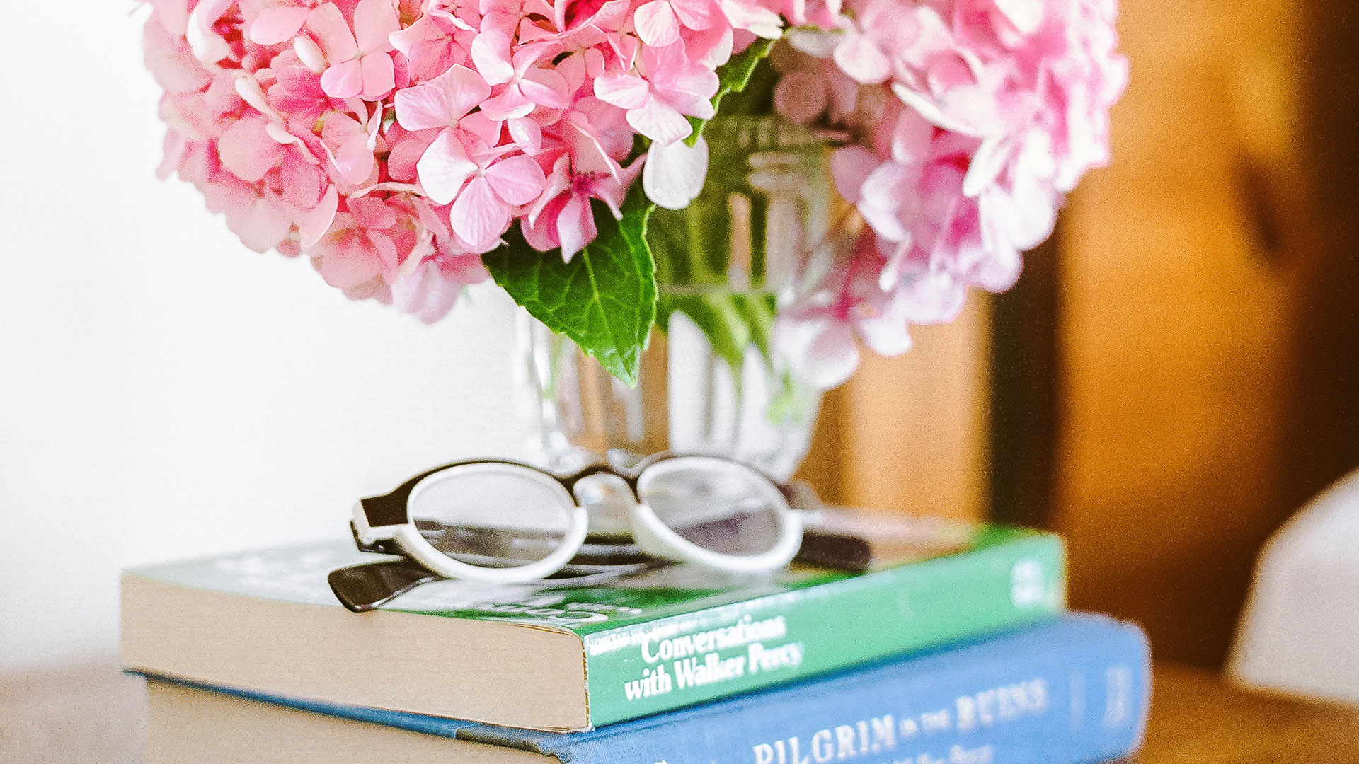 a pink flowers in a vase on top of a stack of books
