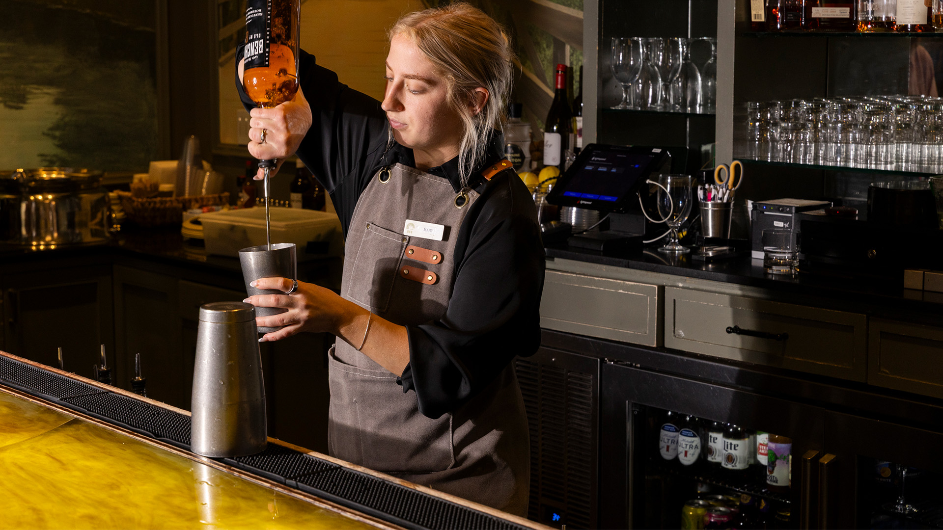 a woman pouring a drink into a shaker