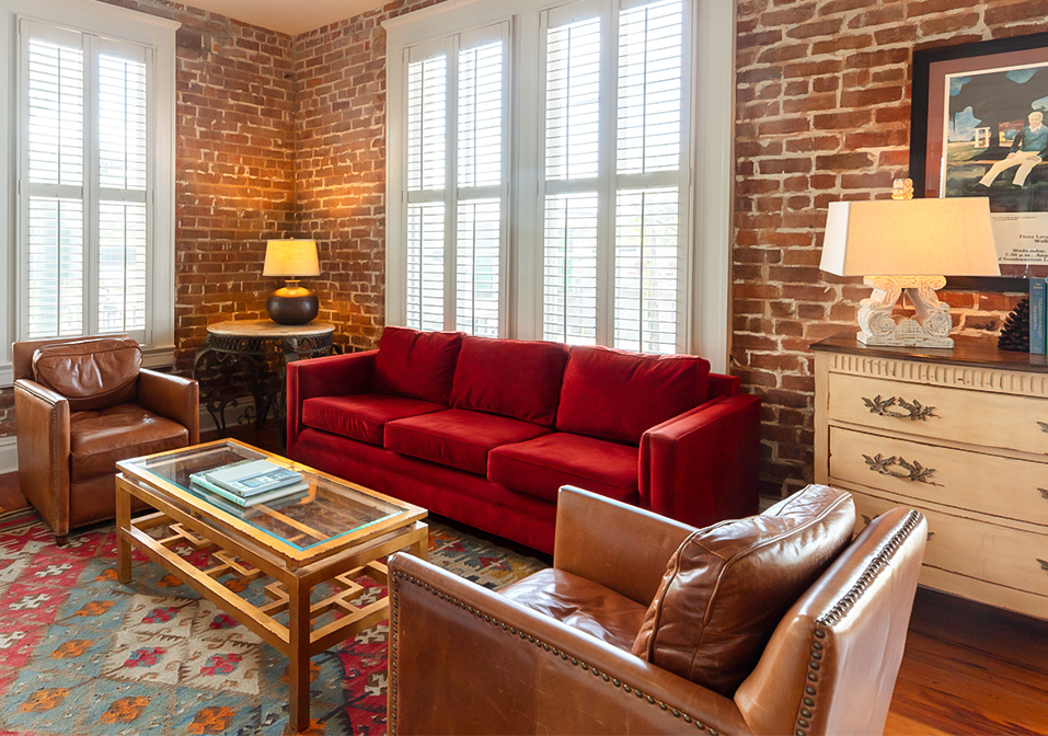 a living room with red couches and a brick wall