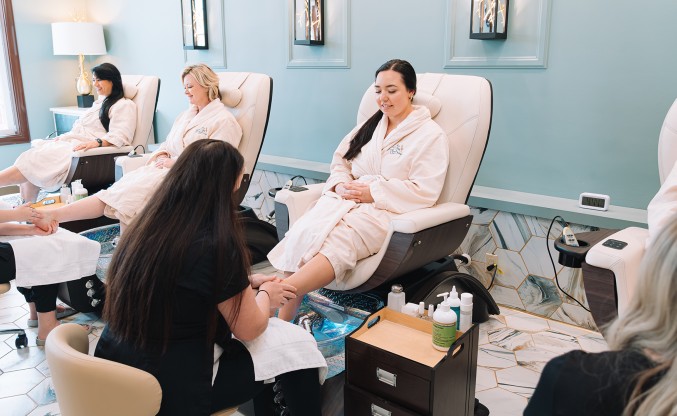 a woman in a bathrobe getting her foot massage
