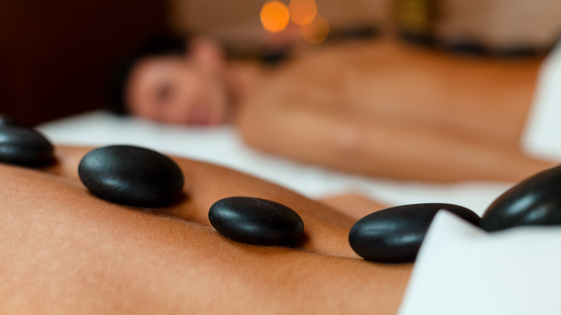 a person lying down with black stones on their stomach