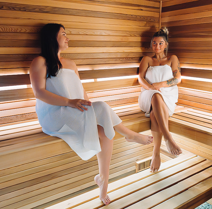 two women sitting on a bench in a sauna