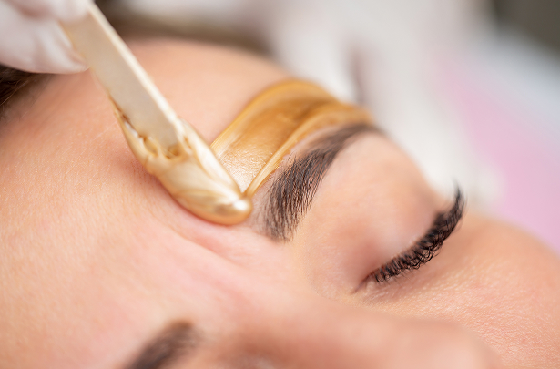 a person getting a gold liquid on their eyebrows