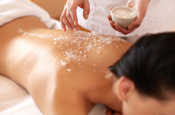 a person scrubbing salt on a woman's back