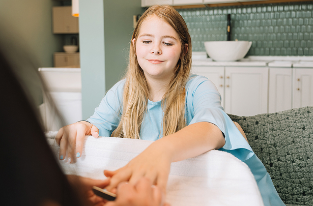 a girl sitting at a table with a nail file