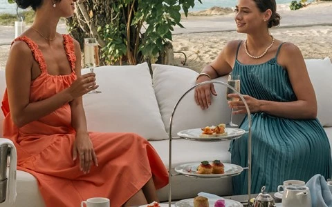two women sitting on a couch drinking tea