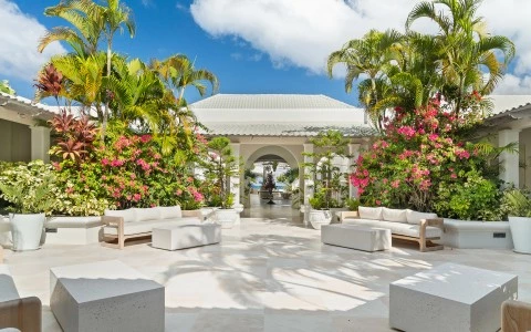 a courtyard with white furniture and a building with a large archway