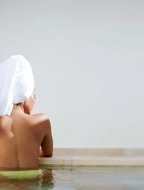 a woman with a towel wrapped on her head in a spa bath